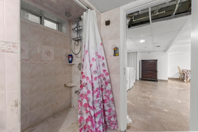 bathroom with a drop ceiling and a tile shower