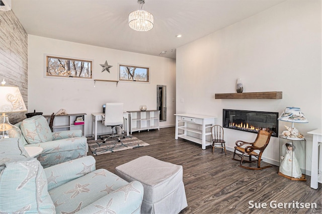 living room with baseboards, recessed lighting, an inviting chandelier, wood finished floors, and a glass covered fireplace