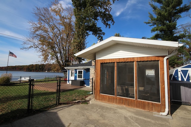 back of house with a gate, fence, a water view, and a yard