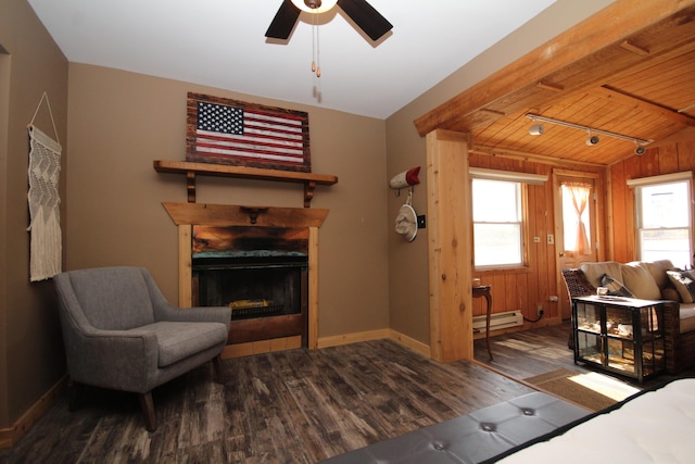 living room with a baseboard heating unit, baseboards, a fireplace, wood finished floors, and a ceiling fan