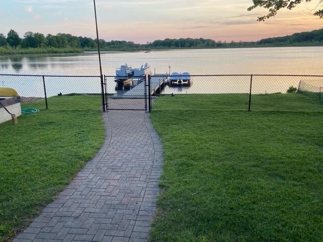 exterior space with a water view, fence, and a gate