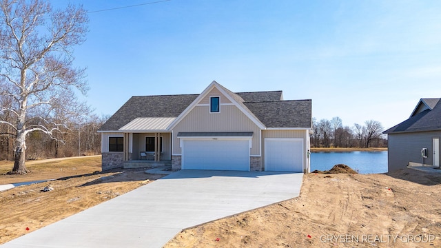 view of front of property with stone siding, driveway, an attached garage, and a water view