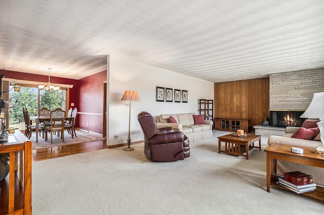 carpeted living area featuring wooden walls, a notable chandelier, and a fireplace