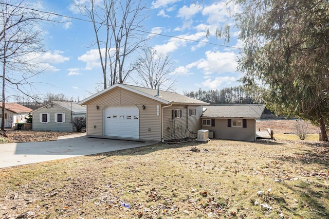 view of front facade featuring central air condition unit, a detached garage, and concrete driveway