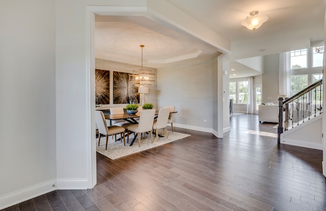 dining area featuring baseboards, a chandelier, stairway, a tray ceiling, and dark wood-style floors