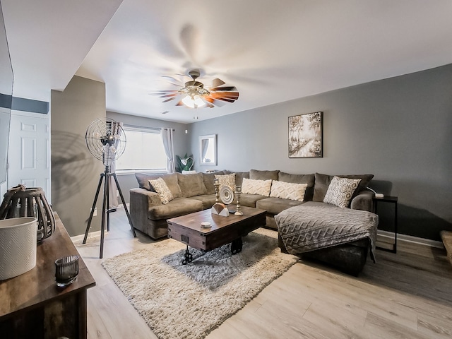 living area with wood finished floors, a ceiling fan, and baseboards