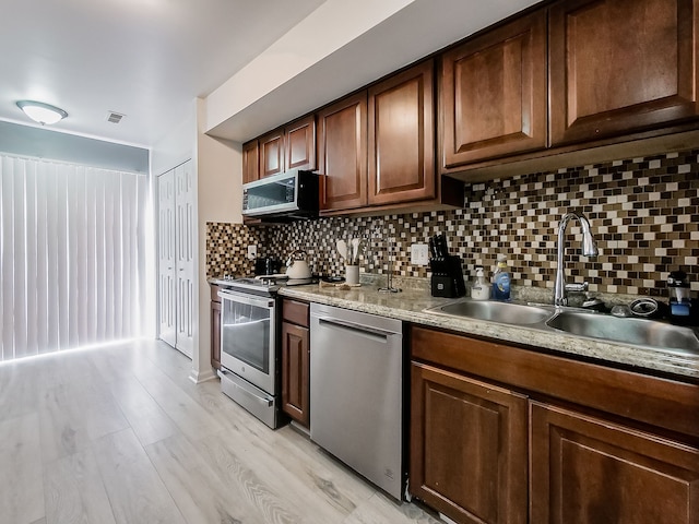 kitchen featuring visible vents, light wood finished floors, a sink, appliances with stainless steel finishes, and backsplash