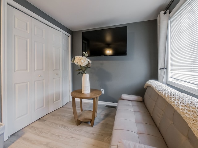 living room with light wood finished floors, visible vents, and baseboards