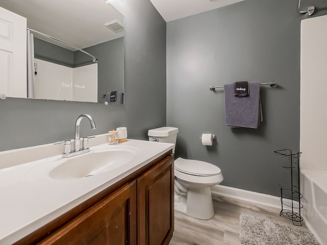 full bath with visible vents, a washtub, toilet, wood finished floors, and vanity