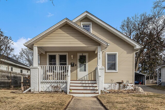 bungalow-style house featuring a carport, covered porch, and fence