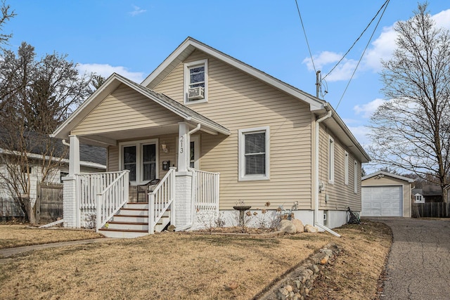 bungalow featuring an outbuilding, driveway, a detached garage, fence, and covered porch