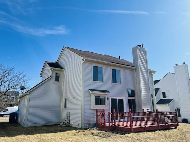 rear view of property with a wooden deck, a yard, and a chimney