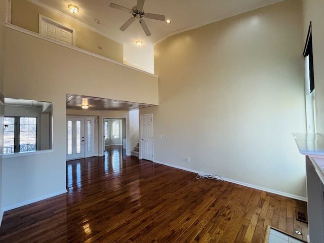 unfurnished living room featuring baseboards, a ceiling fan, a towering ceiling, and wood-type flooring