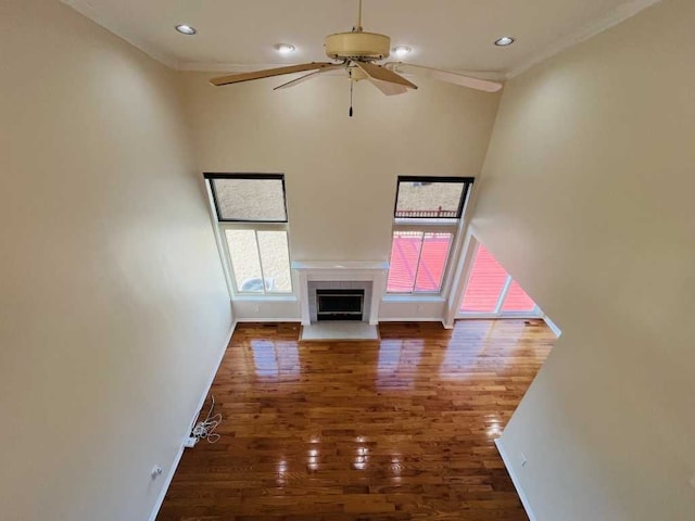 unfurnished living room with a fireplace with flush hearth, ornamental molding, a ceiling fan, and wood finished floors