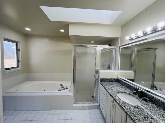 full bathroom with vanity, a skylight, a stall shower, a whirlpool tub, and tile patterned floors