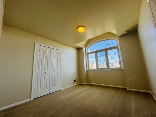 unfurnished bedroom featuring vaulted ceiling, a closet, baseboards, and carpet floors