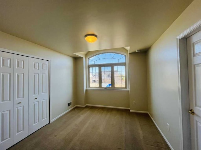 unfurnished bedroom with a closet, carpet flooring, baseboards, and visible vents