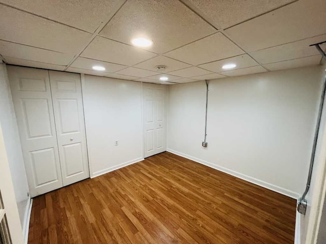 finished below grade area featuring recessed lighting, wood finished floors, baseboards, and a paneled ceiling