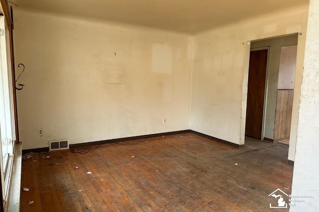 spare room with hardwood / wood-style floors, baseboards, and visible vents