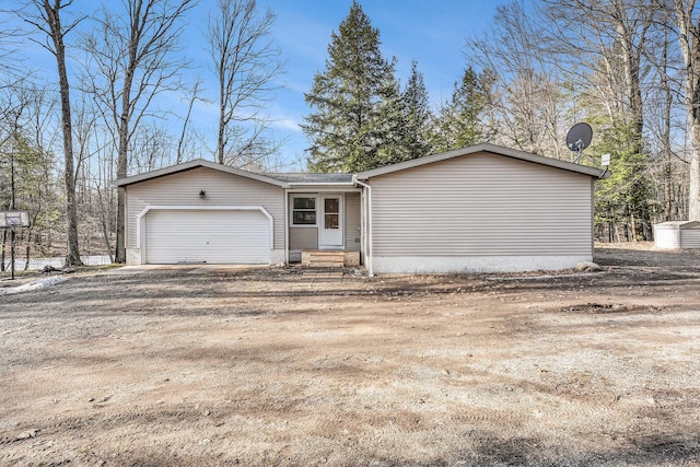 view of front facade with entry steps, an attached garage, and dirt driveway