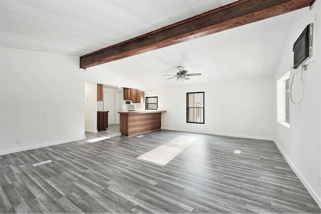 unfurnished living room with a wealth of natural light, wood finished floors, vaulted ceiling with beams, and ceiling fan