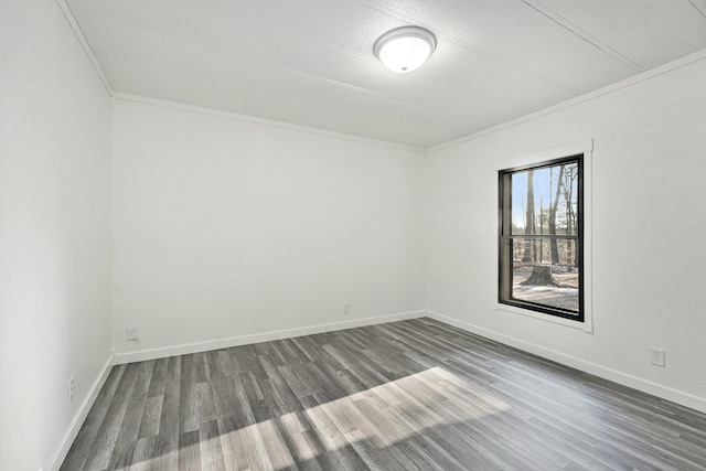 spare room with ornamental molding, baseboards, and wood finished floors