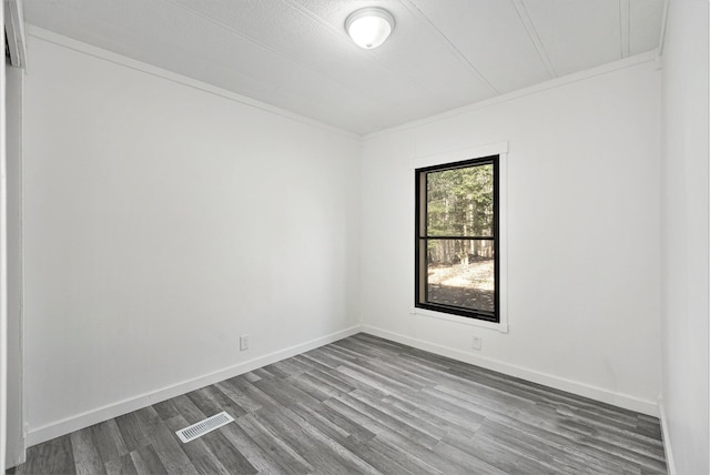 empty room featuring dark wood-style floors, visible vents, and baseboards