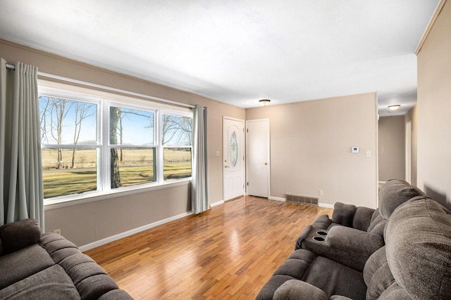 living area with light wood-style flooring, baseboards, and visible vents