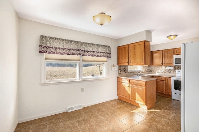 kitchen with visible vents, tasteful backsplash, range with electric stovetop, freestanding refrigerator, and light countertops