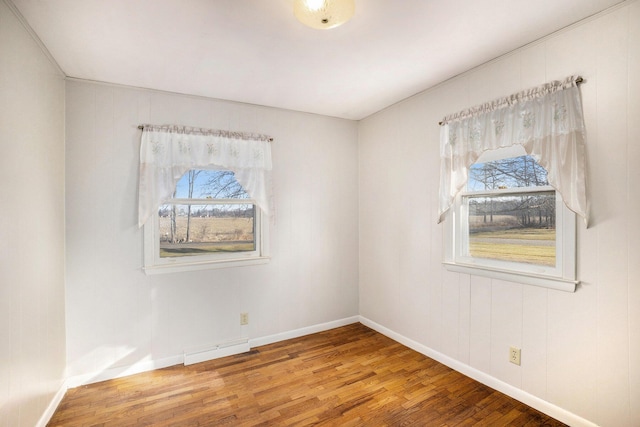 unfurnished room featuring hardwood / wood-style flooring, a healthy amount of sunlight, and baseboards