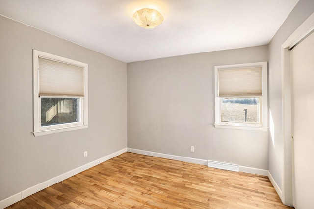 spare room featuring visible vents, plenty of natural light, light wood-style floors, and baseboards