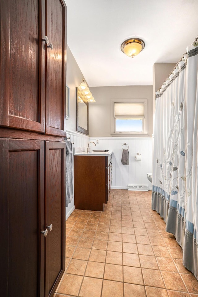 bathroom featuring vanity, visible vents, a wainscoted wall, tile patterned floors, and toilet