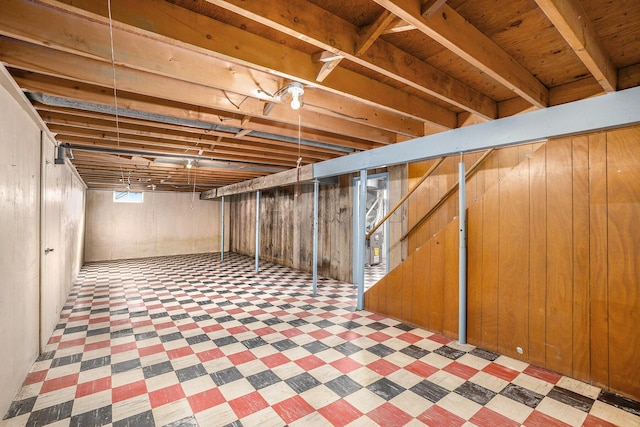 below grade area with stairs, tile patterned floors, and wooden walls