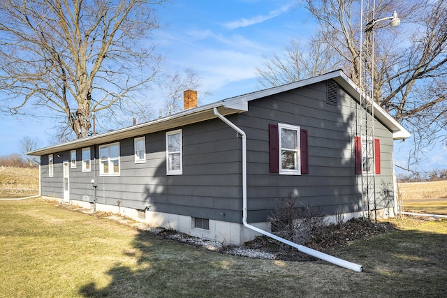 view of side of property with a yard and a chimney