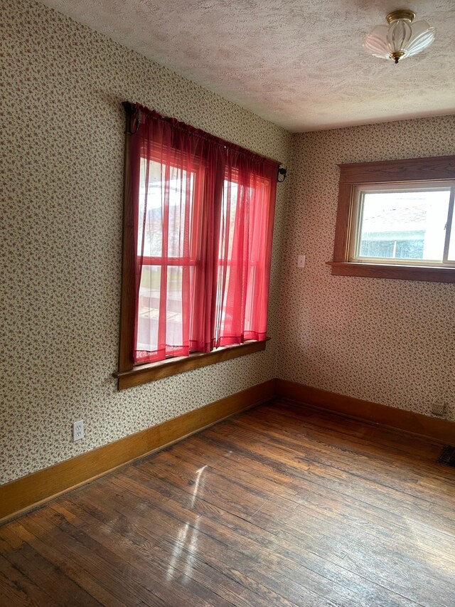 1406 W Ottawa St W, Lansing, MI 48915 - unfurnished room with hardwood / wood-style floors, baseboards, a textured ceiling, and wallpapered walls