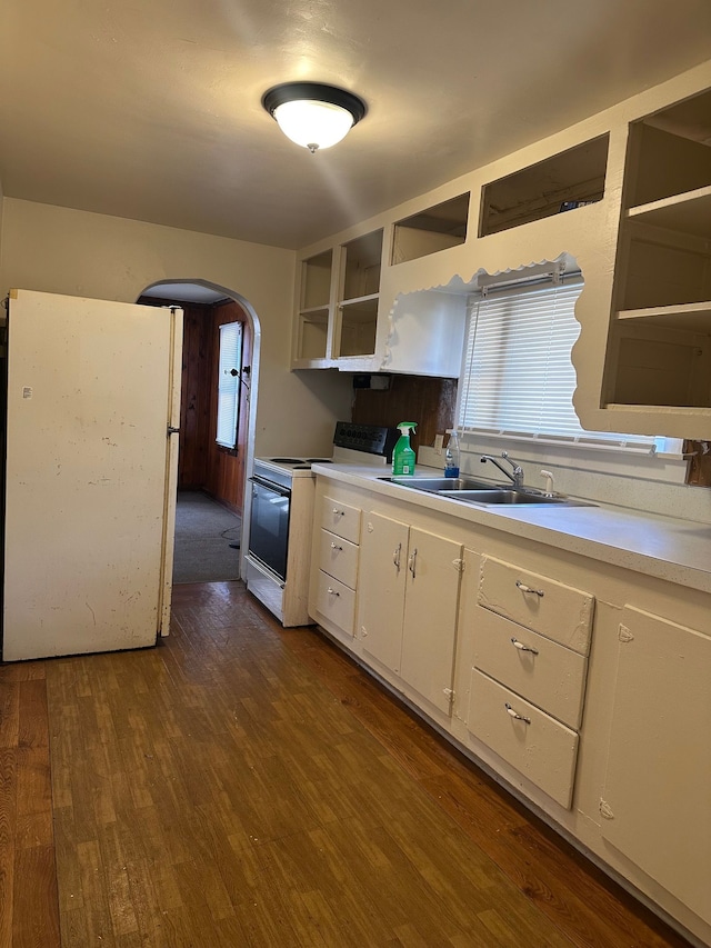 kitchen with open shelves, white appliances, arched walkways, and light countertops