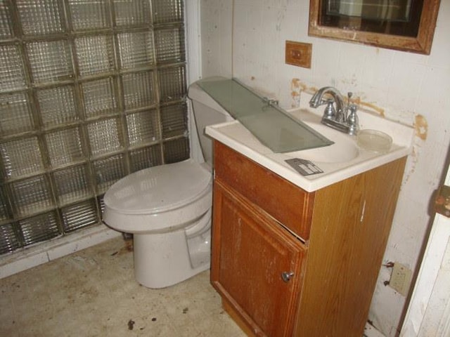 half bath with toilet, tile walls, and vanity