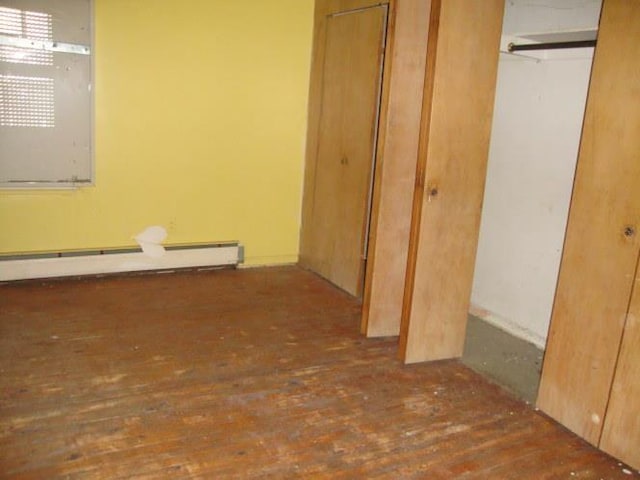 unfurnished bedroom featuring a baseboard heating unit and hardwood / wood-style flooring