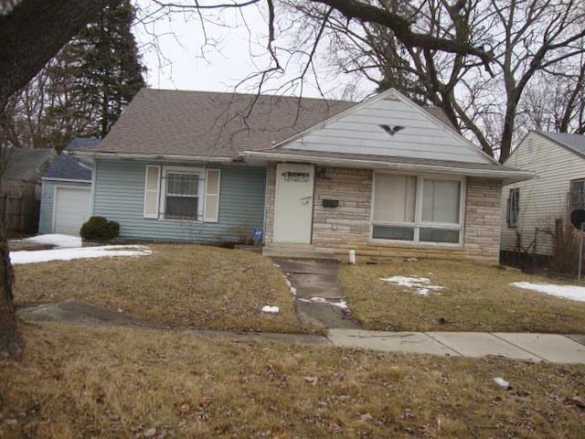 view of front of property featuring a garage, stone siding, and a front lawn