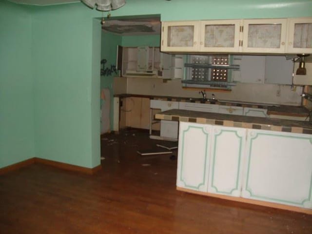 kitchen featuring glass insert cabinets, baseboards, tile countertops, dark wood-style floors, and white cabinetry