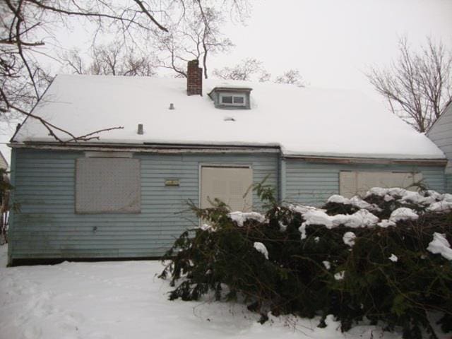 snow covered back of property with a chimney