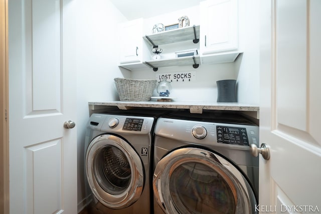 washroom featuring cabinet space and washing machine and clothes dryer