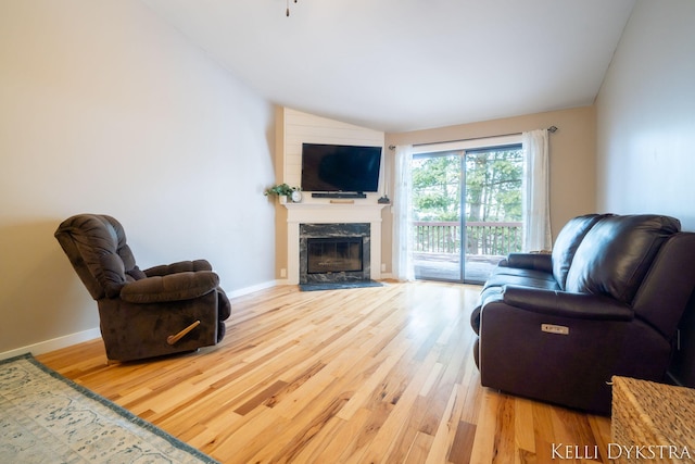 living room featuring baseboards, lofted ceiling, wood finished floors, and a fireplace