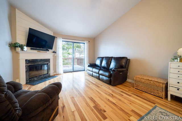 living area with a fireplace, wood finished floors, baseboards, and vaulted ceiling