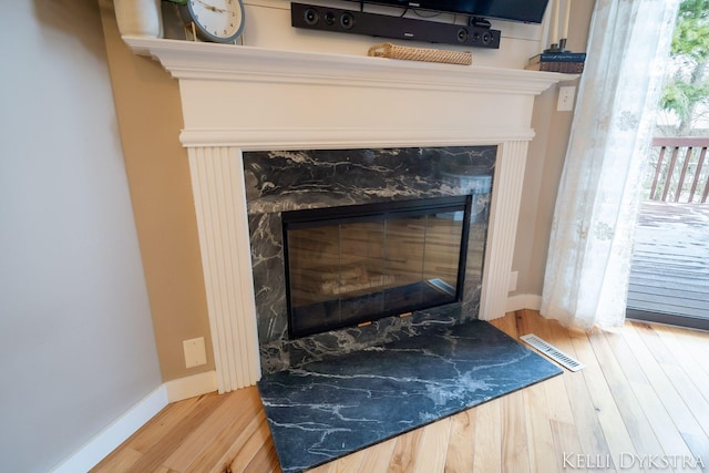 details with visible vents, wood finished floors, baseboards, and a premium fireplace