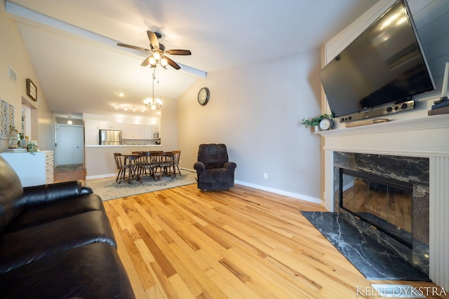 living room with wood finished floors, visible vents, baseboards, a fireplace, and vaulted ceiling