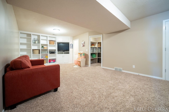 living room with a textured ceiling, light colored carpet, visible vents, and baseboards