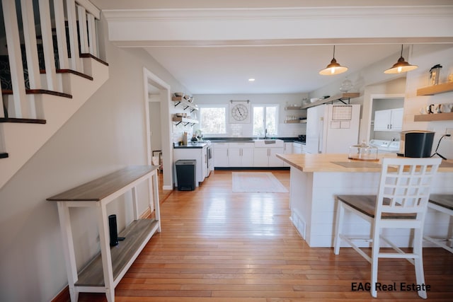 kitchen featuring open shelves, light wood-style floors, a breakfast bar area, and freestanding refrigerator