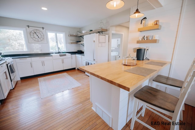 kitchen with open shelves, a sink, white appliances, a peninsula, and decorative backsplash