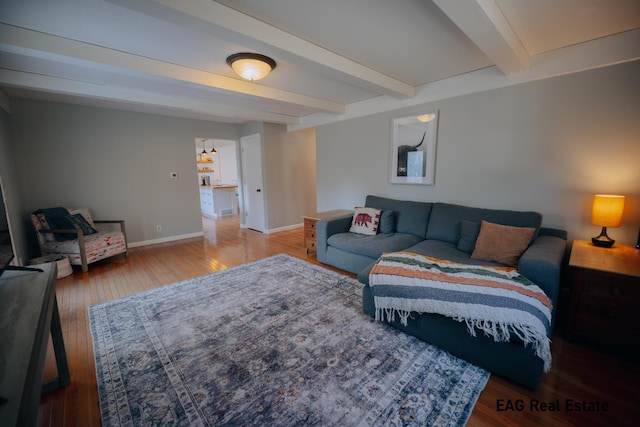 living room with beam ceiling, hardwood / wood-style flooring, and baseboards